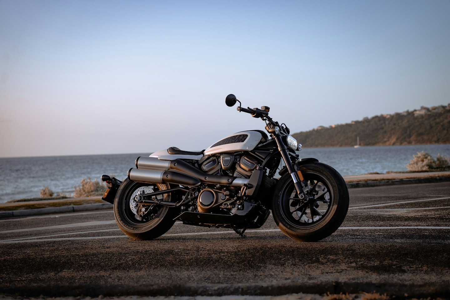 Black and grey motorcycle parked on an asphalt coastal road.